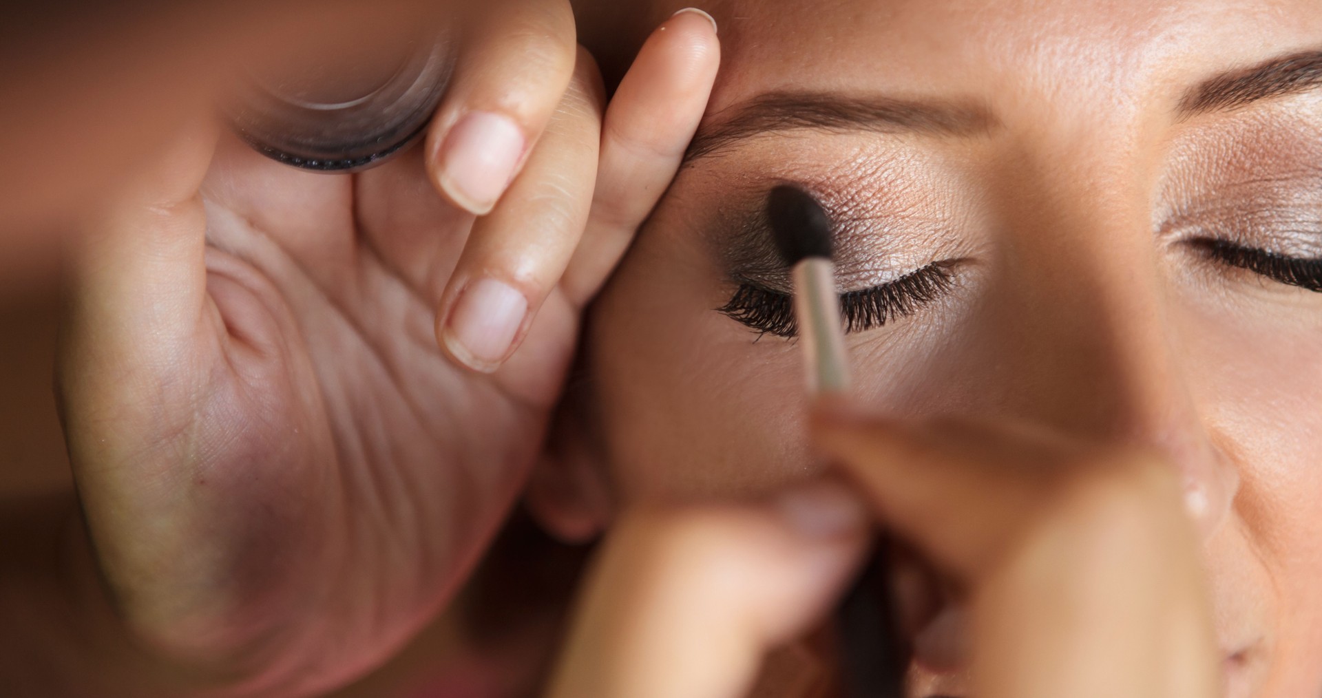 Beautiful girl applying make-up for her wedding by make-up artist